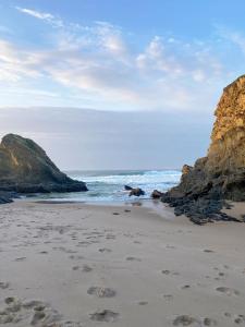 a beach with rocks and footprints in the sand at Casa dos Buizinhos in Porto Covo +15 photos