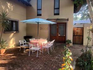 a table and chairs with an umbrella in front of a house at Waterberg Accommodation in Modimolle