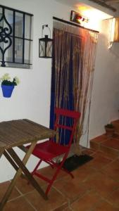 a red chair sitting next to a table in a room at Apartamento casco antiguo Vejer in Vejer de la Frontera