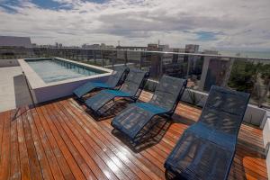 una terraza con 3 sillas y una piscina en un edificio en apartamento para até 4 pessoas, en João Pessoa