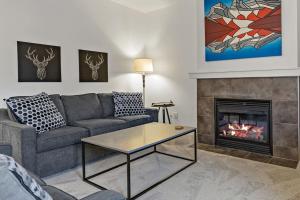 sala de estar con sofá y chimenea en Mountain Retreat - Modern and Bright with Panorama Views 2 bedrooms, 4 beds, heated all-year outdoor pool, hottub, balcony, Banff Park Pass, en Canmore