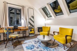 a living room with yellow chairs and a desk and windows at Les Jardins de Coppélia in Pennedepie