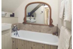 ein Badezimmer mit einer Badewanne, einem Waschbecken und einem Spiegel in der Unterkunft The Old Chapel in St. Davids