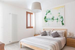 a white bedroom with a bed and a painting on the wall at Casa Marisa - facing campo in Murano - Venezia in Murano