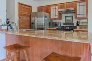 維克拉村莊的住宿－Shores at Waikoloa #108，厨房配有花岗岩台面和木制橱柜