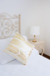 a white bed with a yellow and white pillow on it at Hotel La Pineta Al Mare in Forte dei Marmi