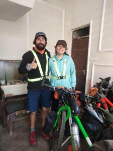Ira Homestay Mathura في ماثورا: رجل وامرأة يقفان بجانب دراجة