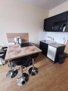- une cuisine avec une table en bois, des tabourets et un évier dans l'établissement Appartement F2 Le Puy-de-Dôme, à Châtel-Guyon