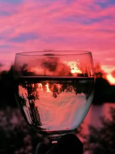 a glass of wine with a sunset in the background at Campingplatz am See - zwischen Berlin und Hamburg in Kamern