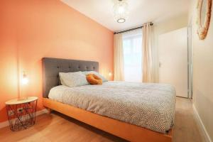 - une chambre avec un lit aux murs orange et une fenêtre dans l'établissement Le Cocon des Jacobins - Rennes Centre, à Rennes