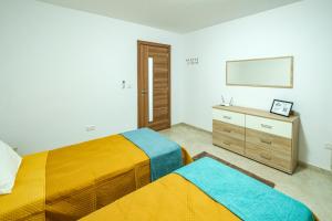 a bedroom with two beds and a dresser and a mirror at Modern 3 bedroom Apartment in Luqa (Sleeps 6) in Luqa