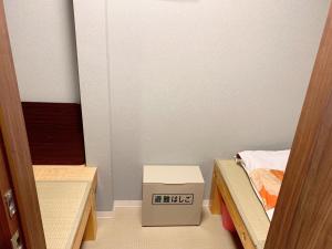 Jing House akihabara Ryokan - Vacation STAY 30899v في طوكيو: غرفة صغيرة بسريرين وصندوق