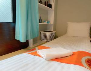 ein Bett mit einer orangefarbenen und weißen Decke drauf in der Unterkunft Jing House akihabara Ryokan - Vacation STAY 30899v in Tokio