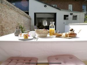 a table with a breakfast of bread and orange juice at La Maison Harmony in Beuvron-en-Auge