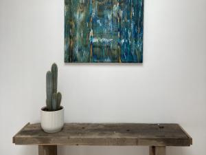 a cactus sitting on a wooden table in front of a painting at La Maison Harmony in Beuvron-en-Auge