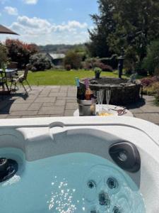 a hot tub with a bunch of drinks in it at Little Acre, a spacious hidden gem with hot tub in Kington