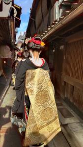 Una donna in un kimono in piedi accanto a un palazzo di Tanaka-ya a Kyoto