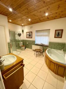a bathroom with a tub and a shower and a sink at Little Acre, a spacious hidden gem with hot tub in Kington