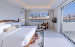 Una habitación de hotel con una cama grande y una ventana grande. en The Chedi Katara Hotel & Resort, en Doha