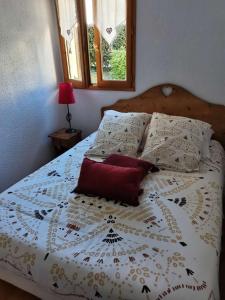 1 dormitorio con cama blanca y almohada roja en Petit cocon entre lac, golf et montagne, proche d'Annecy, en Giez