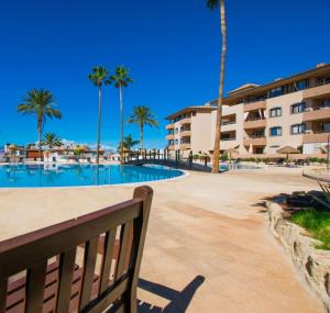 een bankje naast een zwembad met palmbomen bij Peaceful Paraiso in Playa Paraiso