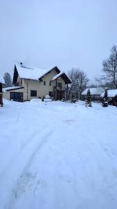 una casa coperta di neve in un cortile di Pensiunea 7 Brazi a Poiana Mărului