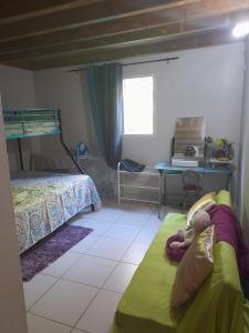 a bedroom with a bunk bed and a child laying on a couch at Un petit coin de Paradis in Deshaies