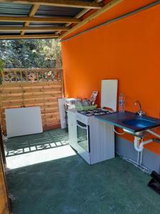 a kitchen with a sink and an orange wall at Un petit coin de Paradis in Deshaies