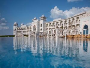 The Chedi Katara Hotel & Resort في الدوحة: مبنى ابيض كبير وامامه ماء