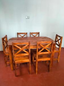 a wooden table with four chairs around it at Mambo Leo Hostel in Paje
