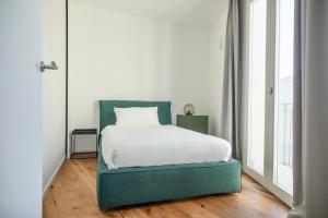 a bedroom with a bed with a green headboard at WeLive Trapani - luxury apartments in Trapani