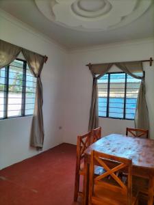 a room with a table and chairs and windows at Mambo Leo Hostel in Paje