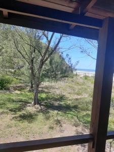 uma janela com vista para uma árvore num campo em Vista da Guarita em Torres