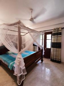 a bedroom with a bed with a mosquito net at Mandara Rest in Hikkaduwa