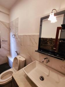 a bathroom with a sink and a toilet and a mirror at Mandara Rest in Hikkaduwa