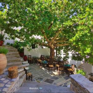 un patio con tavoli e sedie sotto un albero di Fasolas square studio 15m2 is located 30 stairs up from the main road and it is in the old market fasolas and next to the museums a Philotium Altre 16 foto