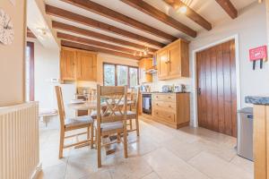uma cozinha com armários de madeira e uma mesa e cadeiras em Tower Cottage Far Sawrey Windermere em Far Sawrey