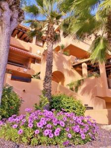 a building with palm trees and flowers in front of it at Luxury large 2 bedroom Apartment short walk to Villamartin Plaza in Villamartin