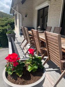 una mesa de madera y sillas en un porche con flores rojas en Balcons de la Semois, en Vresse-sur-Semois