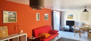 czerwona kanapa w salonie z pomarańczową ścianą w obiekcie Studio en plein coeur de Chanac w mieście Chanac