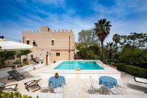 a man sitting in chairs next to a swimming pool at Antica Fortezza Villa Fontana in Valderice
