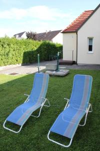 deux chaises de pelouse bleues assises dans l'herbe dans l'établissement Ferienwohnung Kutrowatz, à Rohrbach bei Mattersburg