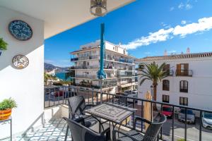 balkon ze stołem i krzesłami oraz budynek w obiekcie Pitufo 1D Apartments Casasol w mieście Nerja
