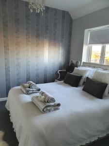 - une chambre avec un grand lit blanc et des serviettes dans l'établissement HOME from HOME GUEST HOUSE, à Rochford