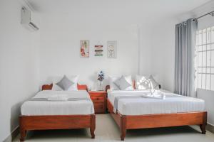 two beds in a room with white walls at White Corner Hotel in Phnom Penh
