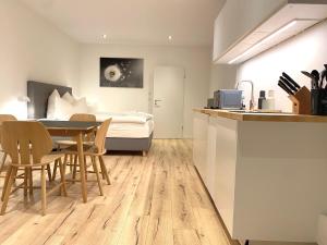 City Lofts Tegernsee - Moderne Studios zentral gelegen في باد ويسي: مطبخ وغرفة طعام مع سرير وطاولة +34 صورة