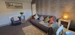 a living room with a couch and a chair at Mains Street Retreat in Lockerbie