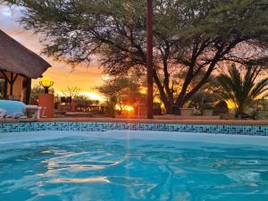 a swimming pool with a sunset in the background at Privathaus mit eigenem Pool - Windhoek in Windhoek