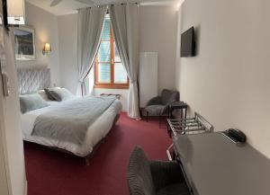 a bedroom with a bed and a desk and a chair at Logis Hôtel des Messageries in Arbois +21 photos
