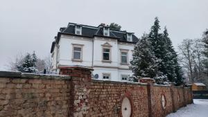 a white house behind a brick wall with snow at Zimmervermietung Villa Meuselwitz in Meuselwitz